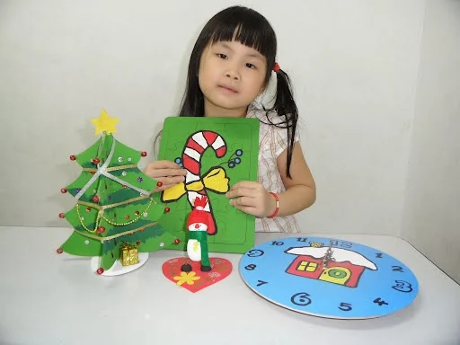 Student with Christmas craft projects — decorated tree and clock
