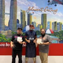 Three members of the My French Factory team in aprons in front of the painted welcome mural