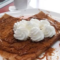 Crêpe dusted with cinnamon sugar and topped with rosettes of whipped cream