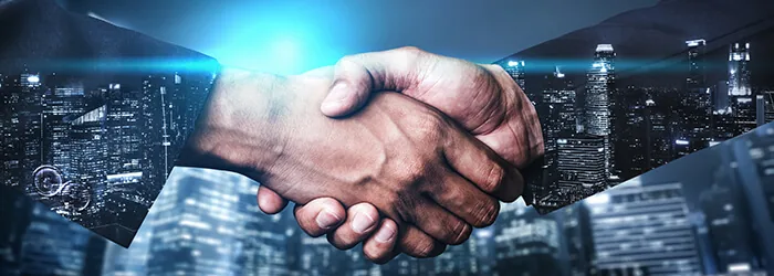 Two business partners shaking hands in front of a city skyline at night